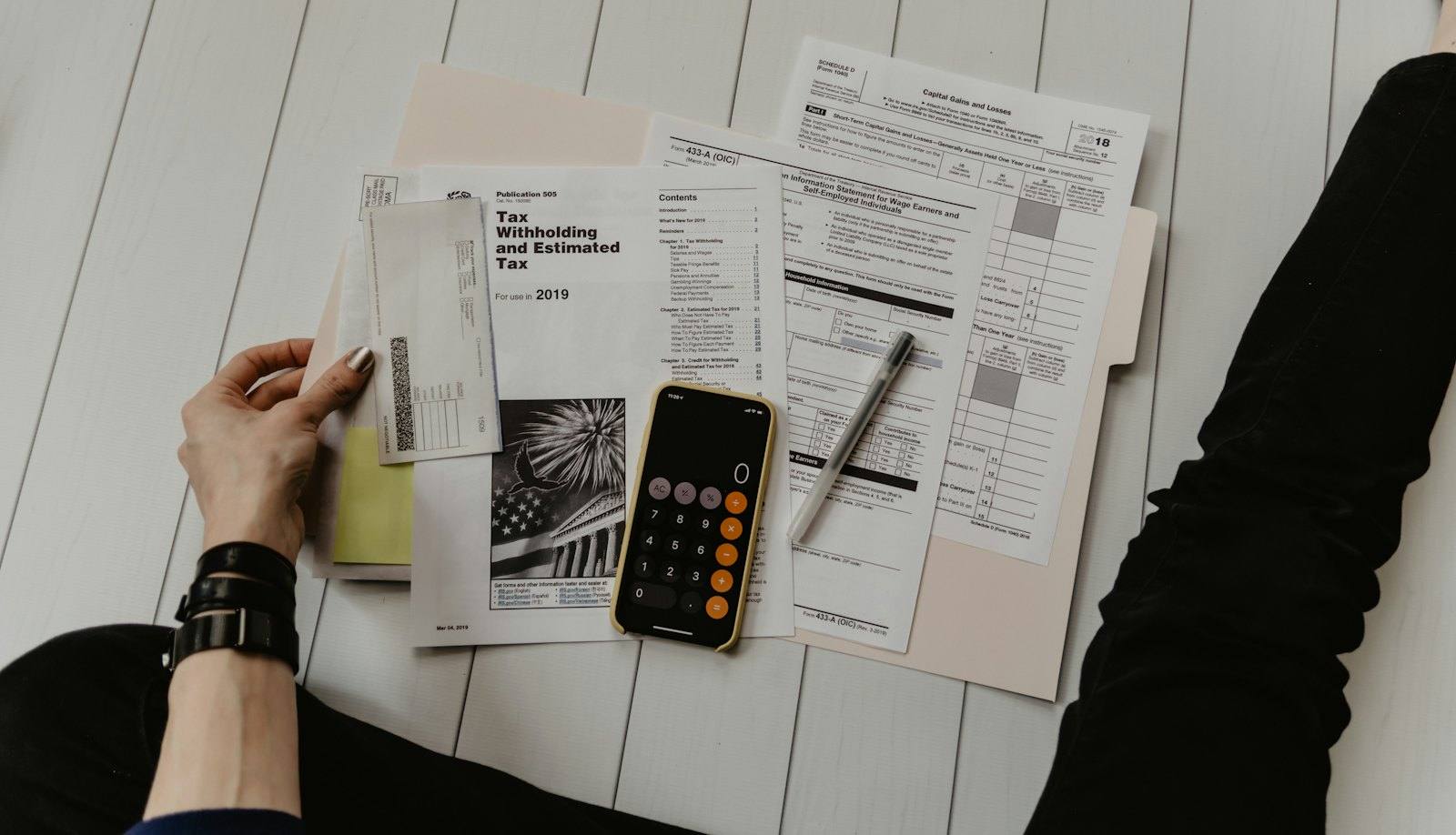 Person reviewing paperwork with a calculator